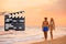 Assistant holding clapperboard and people on beach at sunset. Cinema production