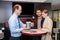 Assistant Showing Compact Speaker To Couple In Shop