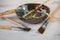 Assorted art paintbrushes randomly placed wooden paint mixing bowl creative background