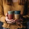 Assorted bamboo travel reusable coffee or tea cups or mags with silicone insulation.One cup with copy-space in female hand