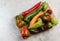 Assorted bell peppers on a rectangular cutting wooden board on a light gray background