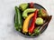 Assorted bell peppers on a round plate on a light gray background