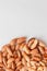 Assorted brown nuts circle on a gray background. Macadamia, cashews, minced almonds, pecans, healthy nutrition. Vertical