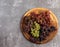 Assorted bunches of ripe grapes on a round wooden cutting board on a dark background