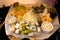 Assorted of cheese with honey, grapes and green olives on cheeseboard or wooden plank. Delicatessen or tasty appetizers