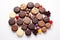 Assorted chocolates on a white table. The chocolates are of different shapes, sizes and colors. Top view