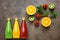 Assorted colored juices in bottles - tomato, orange, kiwi with fruits and mint leaves on a dark background. Top view, flat lay,