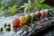 Assorted colorful mochi on a wet stone surface with green leaves in the background