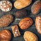 Assorted delicious freshly baked bread on wooden background. Top view of black, brown and white whole grain loaves
