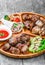 Assorted delicious grilled meat and vegetables with fresh salad and bbq sauce on cutting board on wooden background close up