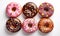 assorted donuts with chocolate frosted, pink glazed and sprinkles donuts.