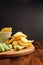 Assorted dry snacks on a wooden board. Chips, peanuts, croutons, wasabi