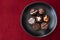 Assorted fancy chocolate candy on a rustic black plate on a red background