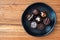 Assorted fancy chocolate candy on a rustic black plate on a wood background