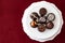 Assorted fancy chocolate candy on a white cake stand on a red background