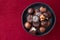 Assorted fancy milk and dark chocolate candy on a rustic black plate on a red background