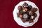 Assorted fancy milk and dark chocolate candy on a white cake plate on a red background