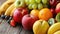 Assorted fresh fruits on a rustic wooden plank.