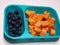 An Assorted Fruit Platter on a Blue tiffin. Papaya, fresh black grapes