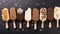 Assorted gourmet ice cream popsicles with toppings on black background