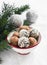 Assorted homemade dark chocolate truffles in a white ceramic bowl, branches of a Christmas tree and Christmas decorations