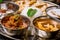 Assorted indian food set on wooden background. Dishes and appetisers of indeed cuisine, rice, lentils, paneer, samosa, spices, mas