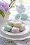 Assorted macarons on a plate with a peony, high tea elegance. AI Generated