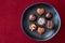 Assorted milk and dark chocolate candy on a rustic black plate on a red background