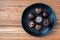 Assorted milk and dark chocolate candy on a rustic black plate on a wood background