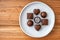 Assorted milk and dark chocolate candy on a rustic white plate on a wood background