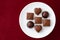 Assorted milk and dark chocolate candy on a white plate on a red background