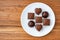Assorted milk and dark chocolate candy on a white plate on a wood background