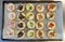Assorted mini quiches on a large metal baking tray, ready for baking