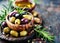 Assorted Olives in a Clay Bowl With Olive Oil and Rosemary on a Rustic Wooden Table