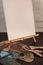 Assorted paintbrushes paint palette art white blank empty canvas easel