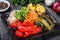 Assorted pickled vegetables - Sauerkraut cabbage, watermelon, peppers, cucumbers, tomatoes and herbs on light wooden background.