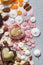 Assorted pink, orange, brown and green chocolate hearts with meringues, pecan nuts and chocolate drops on grey background