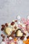 Assorted pink, orange, brown and green chocolate hearts with meringues, pecan nuts and chocolate drops on grey background
