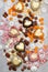 Assorted pink, orange, brown and green chocolate hearts with meringues, pecan nuts and chocolate drops on grey background