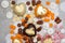 Assorted pink, orange, brown and green chocolate hearts with meringues, pecan nuts and chocolate drops on grey background