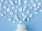 Assorted scattered pharmaceutical medicine pills, tablets and capsules and bottle on blue background. Medicine concept.