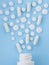 Assorted scattered pharmaceutical medicine pills, tablets and capsules and bottle on blue background. Medicine concept.