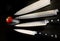 Assorted sharp and shiny kitchen knives are seen with a small tomato in this photograph