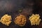 Assorted uncooked pasta treccia, farfalle, whole grain penne on a dark background.