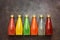 Assorted various colored drinks in bottles on a dark rustic background, border. Top view, flat lay