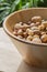 Assorted various nuts in a big wooden bowl against a leafy green background