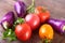 Assorted vegetable with purple exotic color bell peppers and tomatoes on stone background.