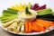 assorted vegetable sticks dipped in hummus on a white plate