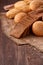 Assortement of bread on burlap on the wooden table. Slices of bread and roll.