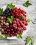 Assortment of berries - raspberries, gooseberries, red currants, cherries, black currants on a white plate on a light rustic